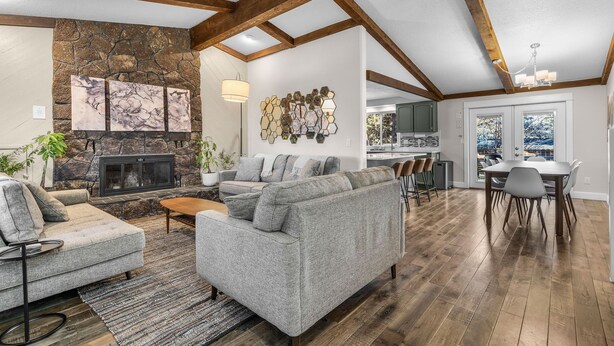 A spacious living area with a stone fireplace, grey sofas, and a dining table with chairs. - New! Hot Tub ~ Foosball ~ Bonus Room ~ Dog Friendly ~ AC! (Bend)