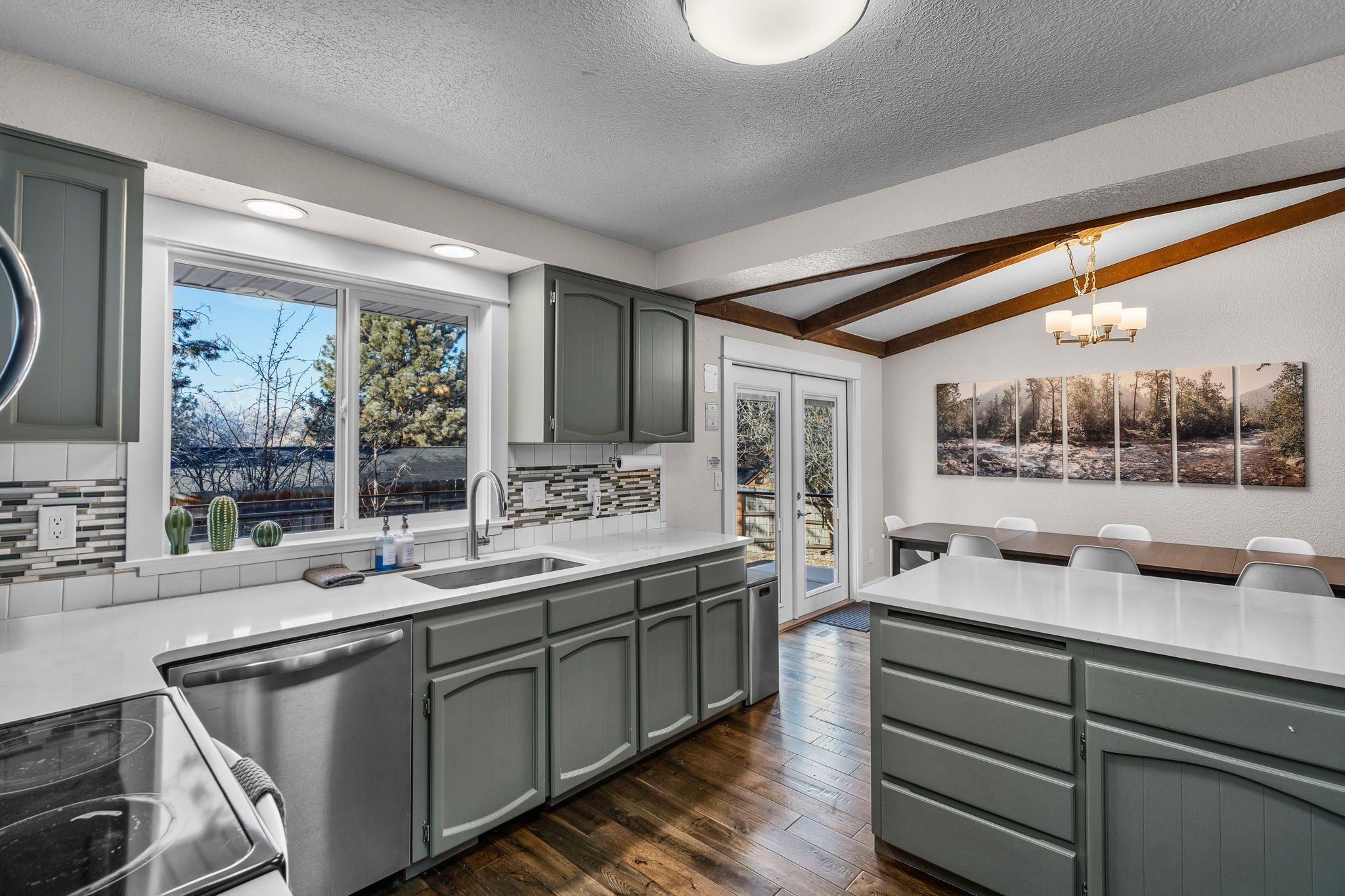 A modern kitchen with grey cabinets, a large island, and a view of the outdoors.