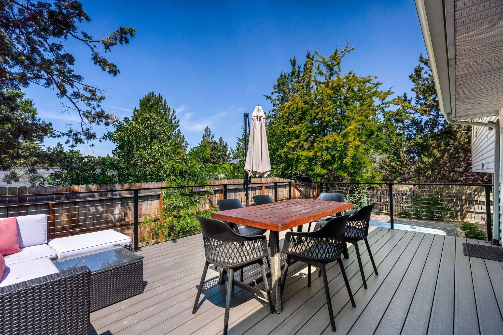 A deck with a table and chairs, a sofa, and a covered umbrella.