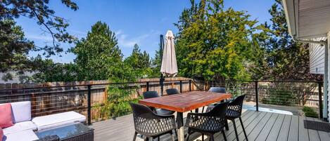 A deck with a table and chairs, a sofa, and a covered umbrella.
