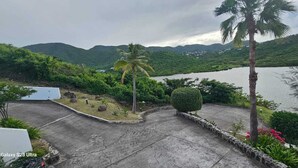 A view of a landscaped area with a body of water, palm trees, and a mountainous backdrop. - Sunset View (Saint Martin)