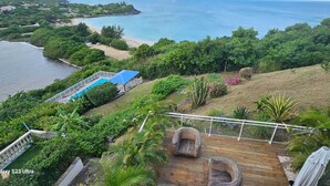 A lush garden with a wooden deck, a pool, and a view of the ocean. - Sunset View (Saint Martin)