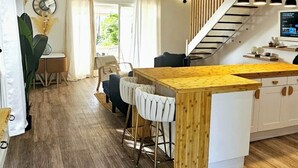 A spacious kitchen with a wooden island, bar stools, and a staircase leading to an upper level. - Sunset View (Saint Martin)
