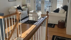 A spacious living room with a high ceiling, a wooden staircase, and a large bay window offering a view of the outdoors. - Waterfront retreat with private dock, hot tub, sauna and spectacular gulf views (Georgetown)