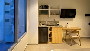 A modern kitchen with a built-in refrigerator, a sink, and a wooden dining table with a chair. A flat-screen TV is mounted on the wall above the counter. - w Impeccable Loft w Charming Terrace in CTG (Cartagena)