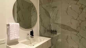 A bathroom with a marble sink, a round mirror, and a glass-enclosed shower. - w Impeccable Loft w Charming Terrace in CTG (Cartagena)