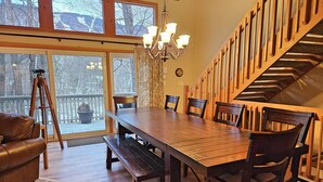 Een eetgedeelte met een houten tafel en stoelen, een kroonluchter en een trap.