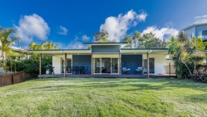A modern house with a covered patio, a lawn, and a clear blue sky. - Bayview • Pet-Friendly Beach House for 6 • Fenced Yard • Walk to Beach (Agnes Water)