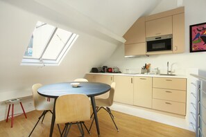 A compact kitchen with a round table and chairs, a skylight, and modern appliances. - Sublime and new Triplex Le Marais/beaubourg (Paris)