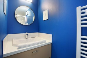 A bathroom with a white sink, a round mirror, and a towel on the counter. - Sublime and new Triplex Le Marais/beaubourg (Paris)