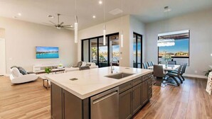 Cozinha moderna com ilha grande, eletrodomésticos de aço inoxidável e iluminação pendente.