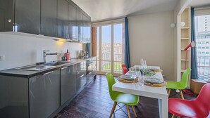 Eine moderne Küche mit Essbereich, großen Fenstern und Blick auf die Stadt.