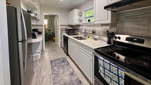 A modern kitchen with white cabinets, a black stove, and a tiled backsplash. - Villa Mars In Marathon (Marathon)