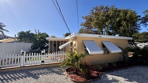 A single-story building with a white picket fence, a small garden with gravel and plants, and a clear blue sky. - Villa Mars In Marathon (Marathon)