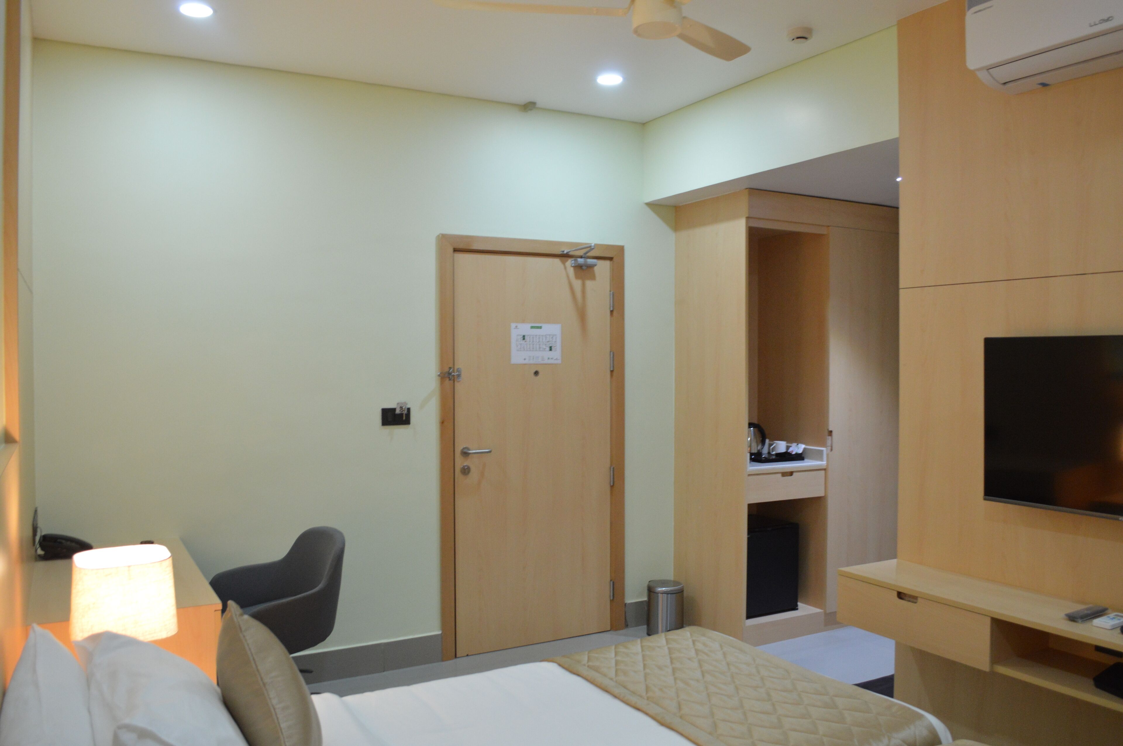 A hotel room with a bed, a desk, a chair, a TV, and a wardrobe.