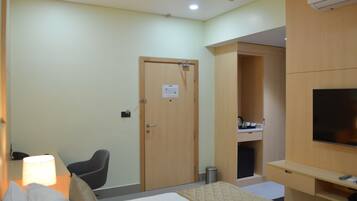 A hotel room with a bed, a desk, a chair, a TV, and a wardrobe.