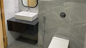 Een moderne badkamer met een marmeren wastafel, een wastafel, een spiegel en een douche.