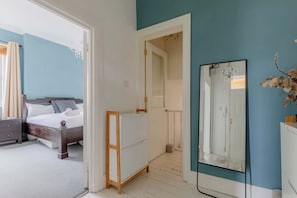 Ein Schlafzimmer mit Bett, Kommode, Spiegel und einer Tür zu einem anderen Raum.