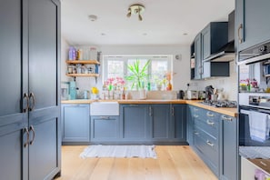 Une cuisine moderne avec des meubles gris, des plans de travail en bois et une fenêtre agrémentée de plantes.