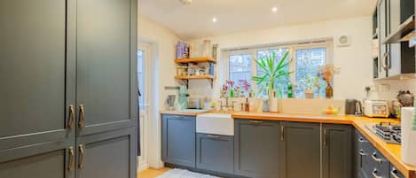 Une cuisine moderne avec des meubles gris, un plan de travail en bois et une fenêtre donnant sur un paysage verdoyant.