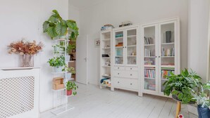 Et værelse med en hvid bogreol, et hvidt konsolbord og et hvidt skab.