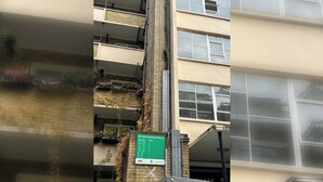 A multi-story building with a green sign indicating flat numbers and corresponding floors.