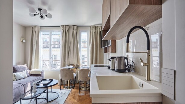 A modern kitchen with a sink, stove, and cabinets. There is a dining area with a table and chairs. - New Apartment Center of Paris/le Marais (Paris)