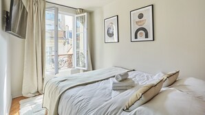A bedroom with a bed, a window with curtains, and two framed pictures on the wall. - New Apartment Center of Paris/le Marais (Paris)