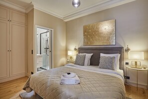 A hotel bedroom with a large bed, bedside lamps, a painting on the wall, and a view of the bathroom. - Sublim new Flat Center of Paris Opera Madeleine (Paris)