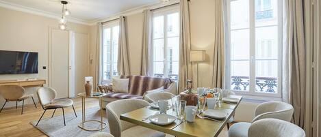 A modern hotel room with a dining area, a sofa, and a television.