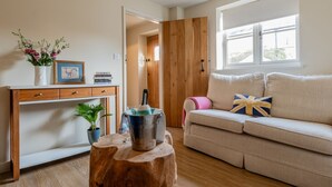Ein Wohnzimmer mit einem Holztisch, einer Couch, einem Fenster und einer Tür zu einem anderen Raum.
