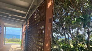 A covered walkway with a view of the ocean, a brick wall, and a wooden fence. - 61 OCEAN ROAD MOTEL  (Skenes Creek)