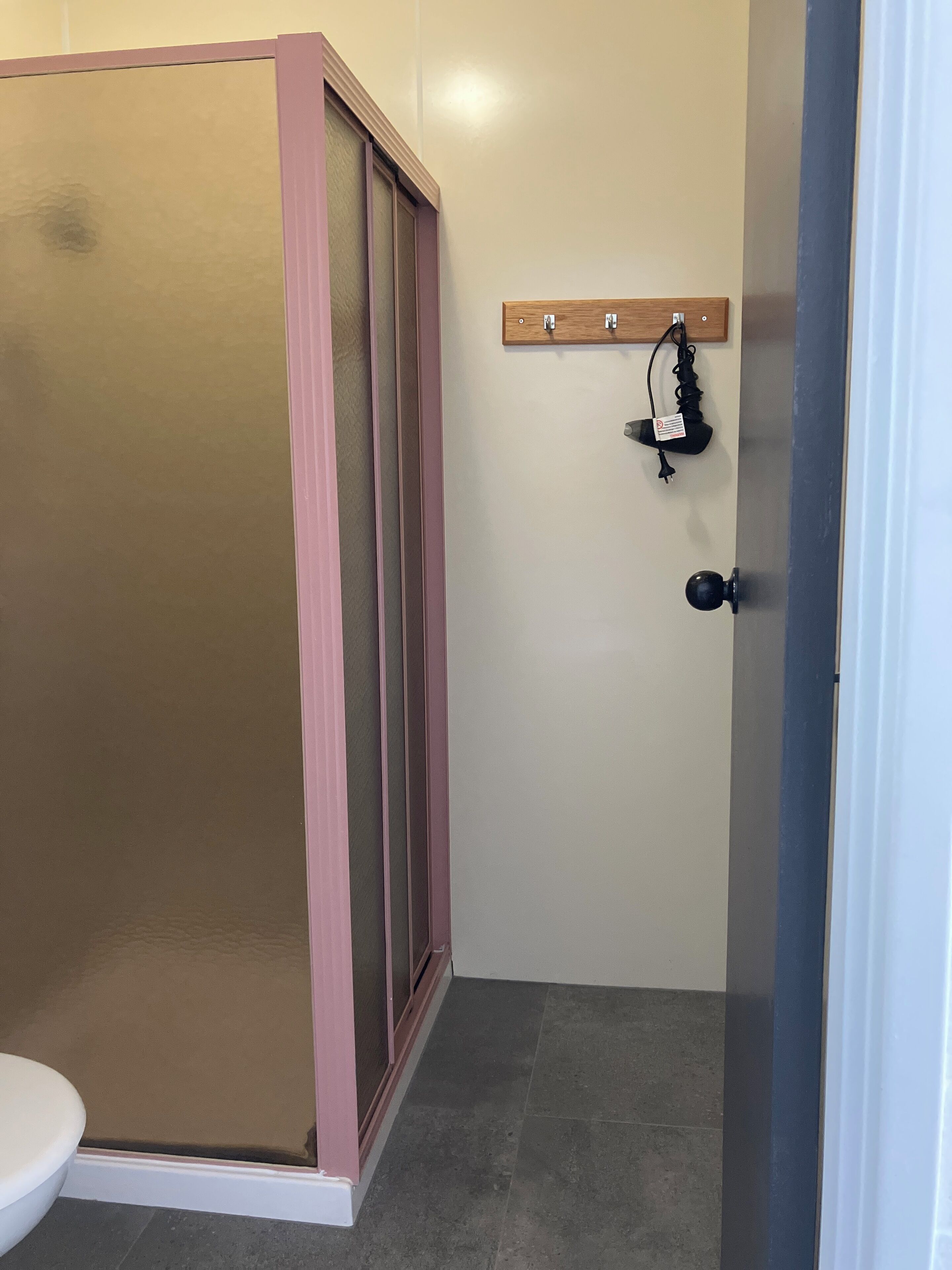 Un baño con cabina de ducha, inodoro y barra para toallas.