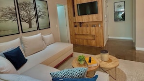 Una sala de estar moderna con un sofá blanco, una mesa de centro con adornos y un televisor de pantalla plana.