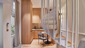 A modern kitchen with wooden cabinets, a built-in stove, and a dining area with a chair and table.