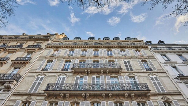 A multi-story building with ornate balconies and shutters.