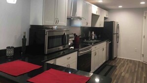 Una cocina moderna con armarios blancos, electrodomésticos de acero inoxidable y encimeras negras.
