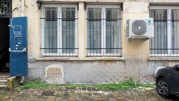 A building with three windows, a blue door, and an air conditioning unit.