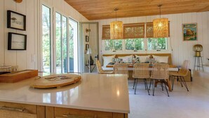 A spacious kitchen with a large island, wooden ceiling, and large windows. - Cap Ferret Villa • 5 Bedrooms • Heated Pool (Lège-Cap-Ferret)