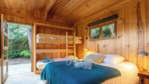 A wooden cabin bedroom with a bunk bed, a single bed, and a window overlooking a forest. - Cap Ferret Villa • 5 Bedrooms • Heated Pool (Lège-Cap-Ferret)