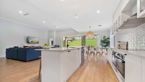 Une cuisine moderne avec un îlot central, un coin repas avec une table et des chaises, et un canapé bleu dans l’espace salon.