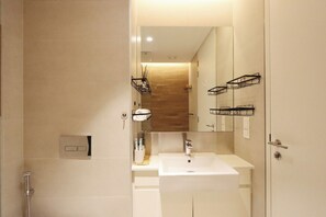 A modern bathroom with a white sink, a mirror, and a shower.