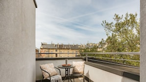 A balcony with two chairs, a small table, and a view of buildings and trees. - A two-level family apartment (Kraków - Kazimierz & Podgórze)
