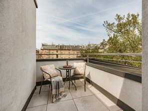 A balcony with two chairs, a small table, and a view of buildings and trees. - A two-level family apartment (Kraków - Kazimierz & Podgórze)