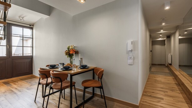 A dining area with a table set for four, wooden flooring, and a view of the adjacent room. - A two-level family apartment (Kraków - Kazimierz & Podgórze)