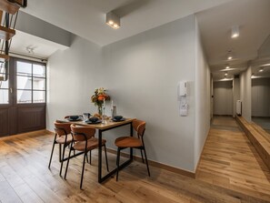 Un coin repas avec une table dressée pour quatre personnes, un plancher en bois et une vue sur la pièce adjacente.
