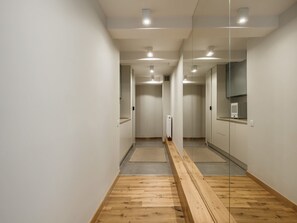 Ein moderner Flur mit Holzboden, weißen Wänden und gespiegelten Türen.