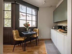 A modern kitchen with a dining area, large windows, and a view of buildings outside. - Studio standard for two. (Kraków - Kazimierz & Podgórze)