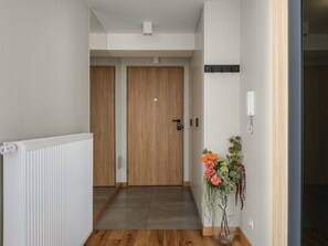 A hallway with a radiator, wooden flooring, a wooden door, and a vase with flowers. - Studio standard for two. (Kraków - Kazimierz & Podgórze)