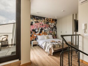 Une chambre moderne avec un grand lit, une table de chevet, une chaise, un balcon et un mur décoré de graffitis.